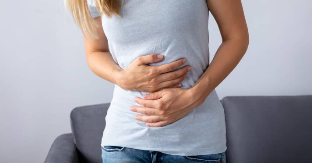 A woman clenches her stomach, How to Increase Your Stomach Acid Naturally