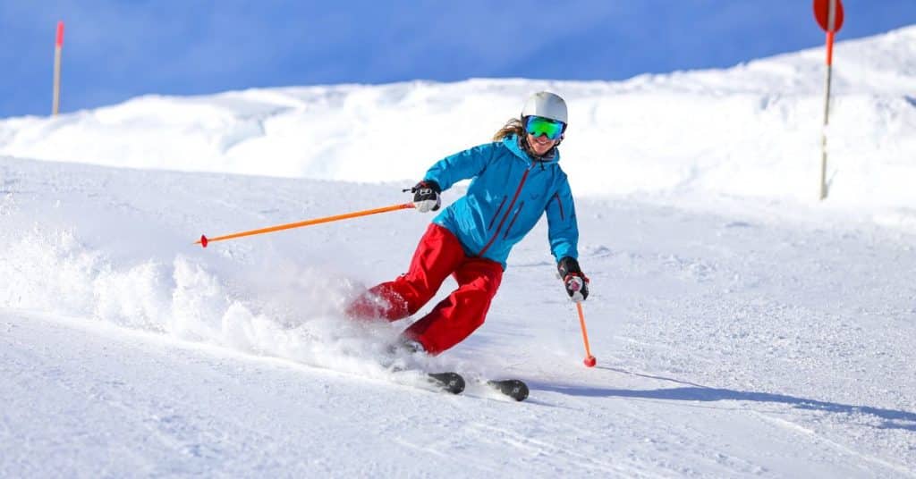 A woman skis down a clean snowy hill with a smile on her face