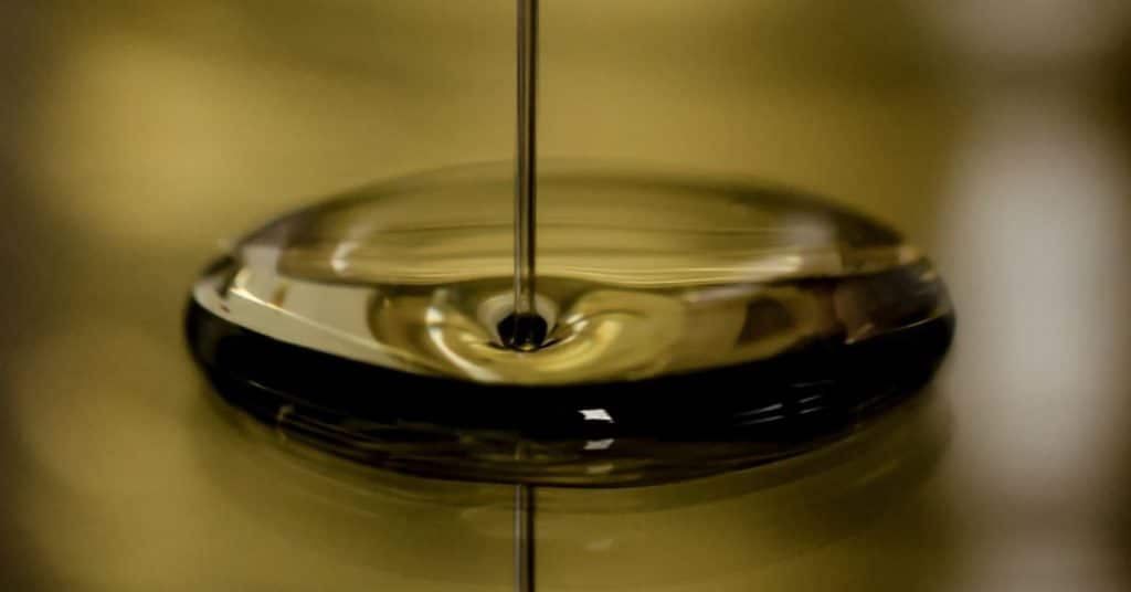 Close up look at sesame oil being drizzled into a larger pool of the oil
