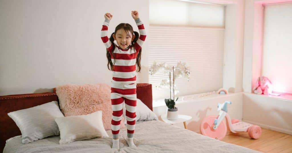 A young child jumps on the bed in her PJ's, What to do When Your 2 Year Old is Contipated and Crying