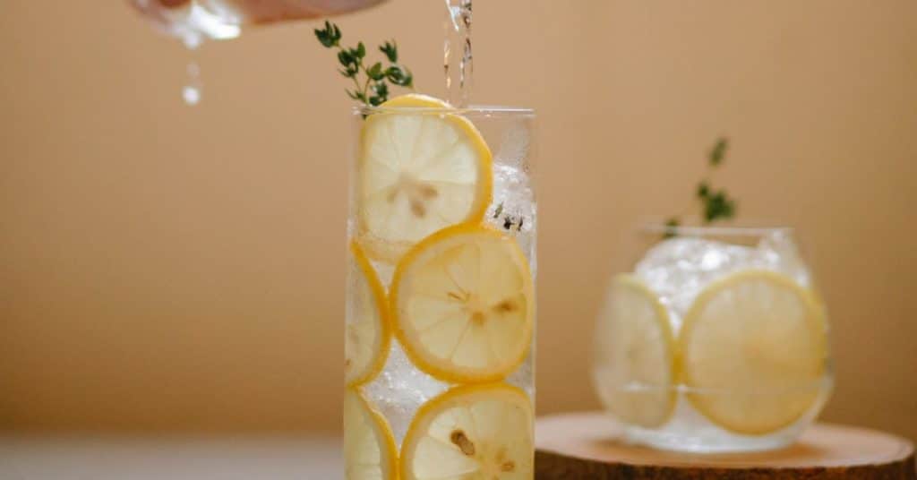 Water glasses filled with ice, water, lemon slices and herbs