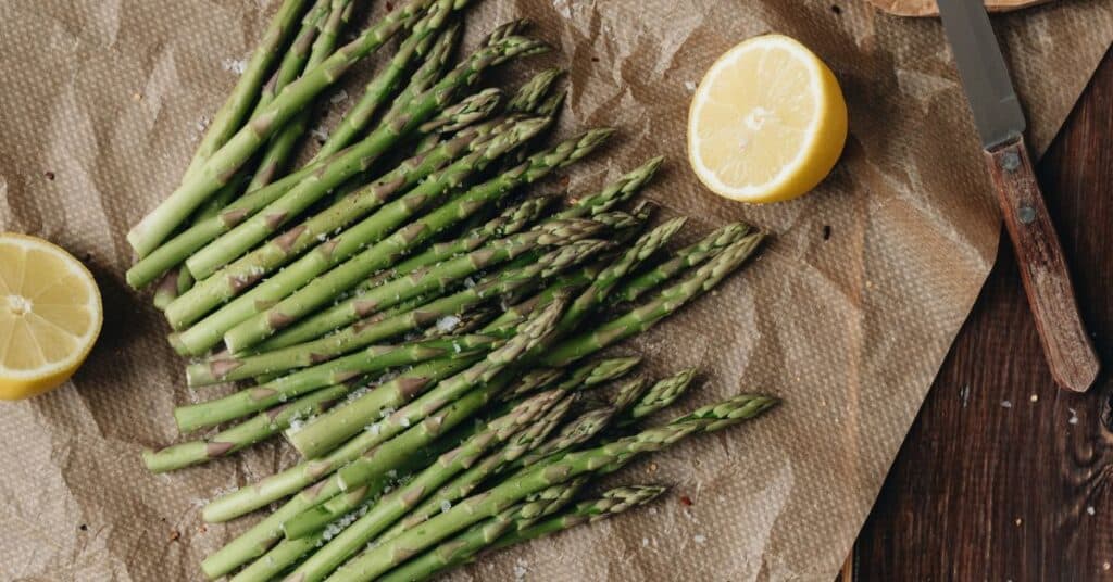 Salted asparagus and halved lemon rest on parchment paper, recipes to help detox