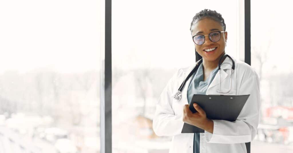 Portrait of a young black doctor with glasses holding a clipboard