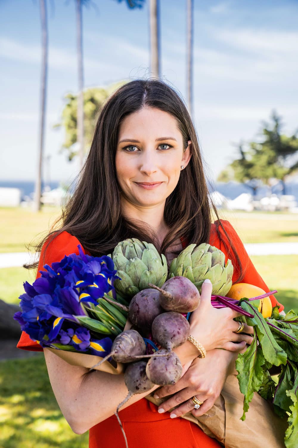 Emily Luxford, autoimmune and food sensitivity dietitian, holds a bunch of veggies from the farmers market