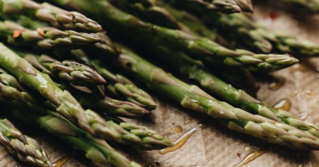 Oiled stalks of asparagus laid out on parchment paper
