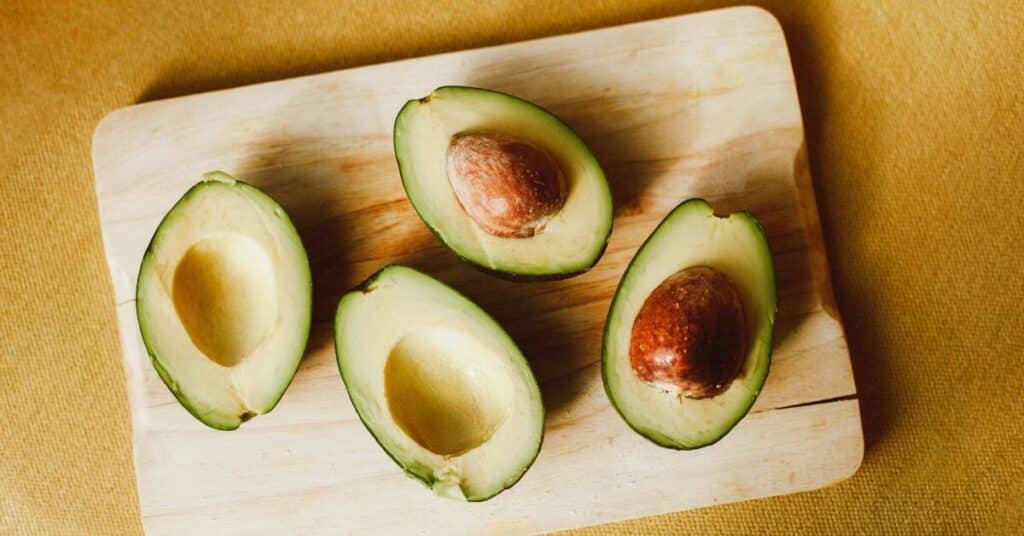 Two halved avocadoes on a wooden cutting board