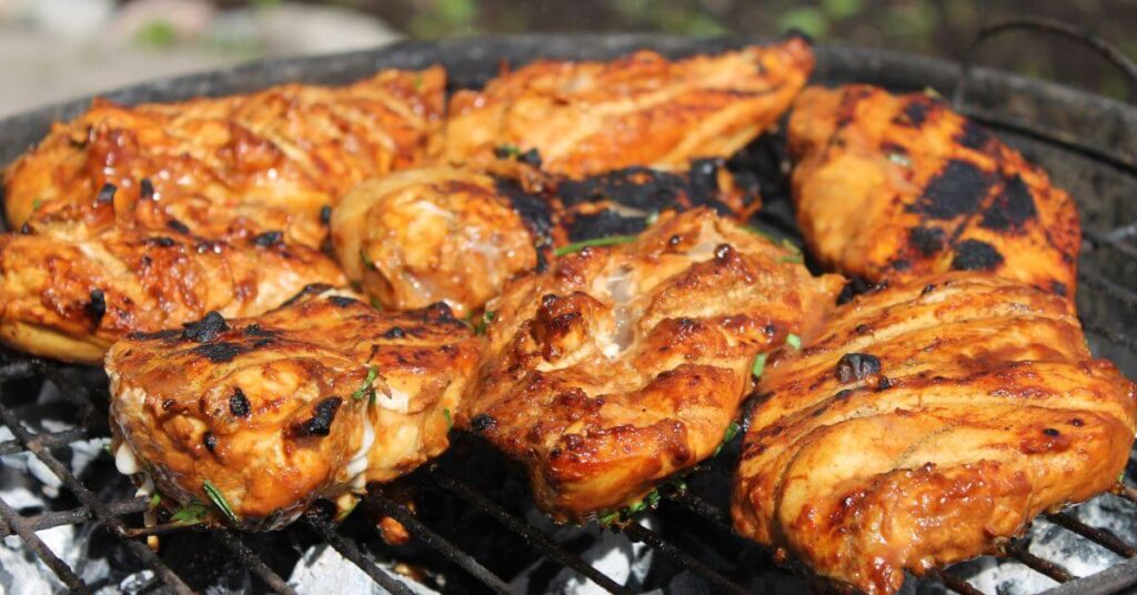 8 barbecued chicken breasts set on a grill, bulk cooking