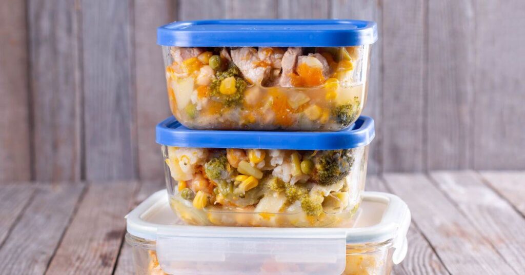 Glass food storage containers stacked, each with a chicken and vegetable soup