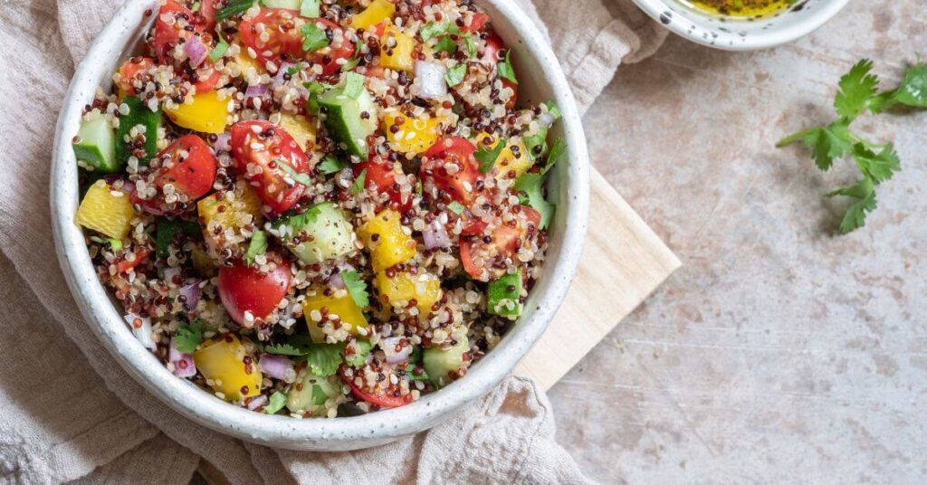 Quinoa salad in a bowl topped with fresh veggies and herbs, how to go gluten free