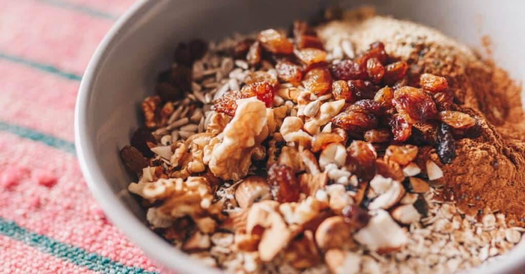 A bowl of oats, topped with nuts, spices and dried fruits, high fiber for what to eat after giving birth and breastfeeding