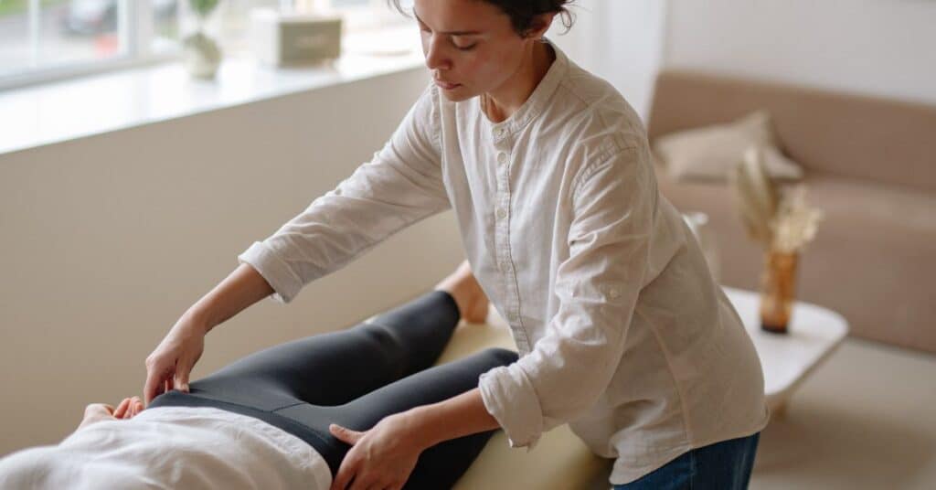 A physical therapist looks at a female's hips as she lies on a table, nutrition and physical therapy