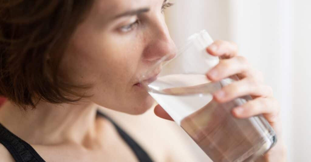 A woman sips out of a glass of water