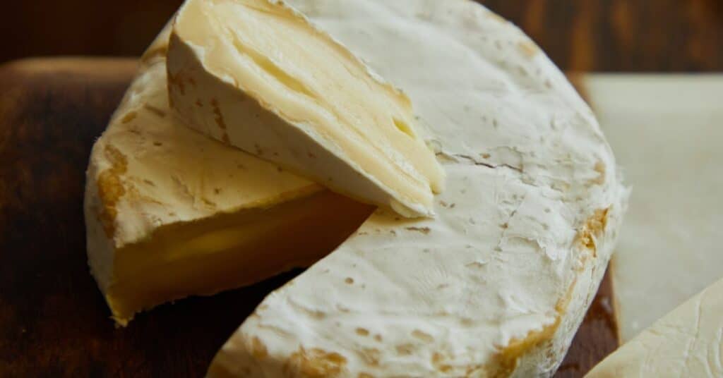 Large wheel of brie cheese with a hunk cut out of it, food sensitivity headache