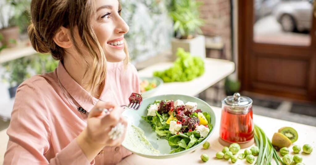 Happy woman enjoying a salad with colorful veggies, intermittent fasting