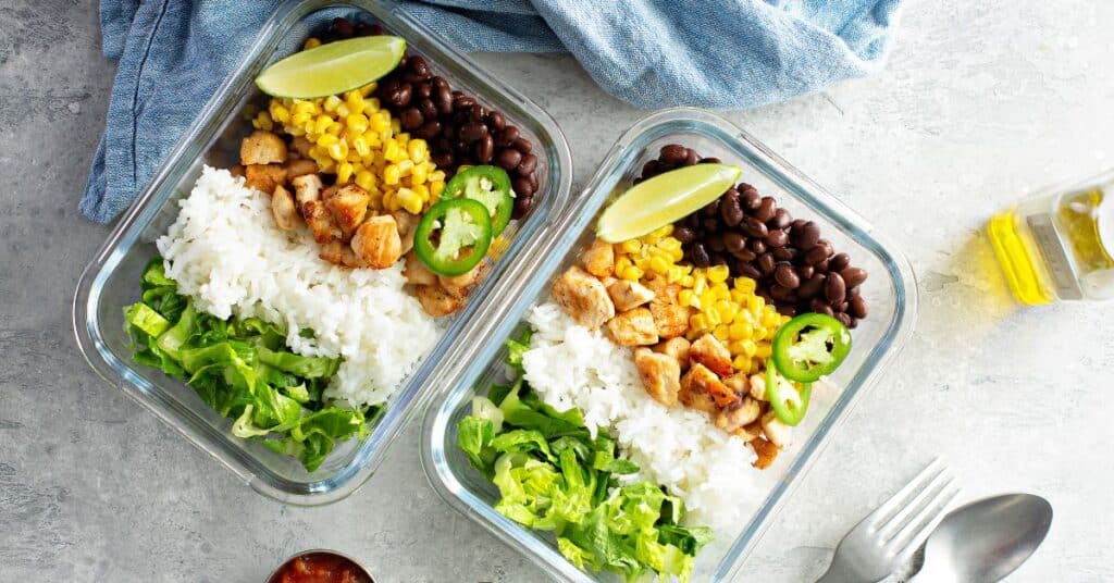 Two meal prep containers with rice, lettuce, chicken, corn and bean, intermittent fasting