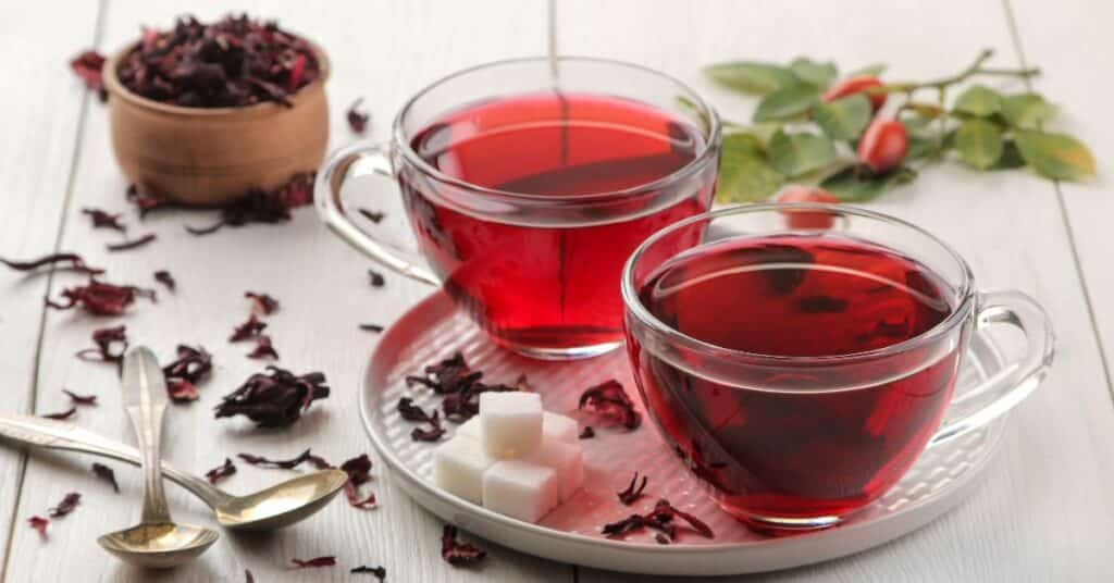 Hibiscus tea in two clear glass mugs rest on a large coaster