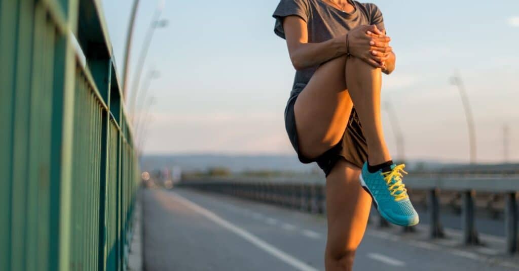 Woman stretching her knee standing on the road