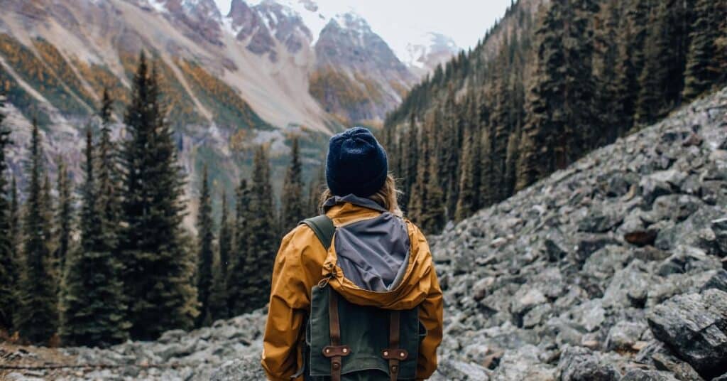 Woman wearing a yellow coat and blue beanie while hiking on a rocky mountain, keto diet advantages and disadvantages