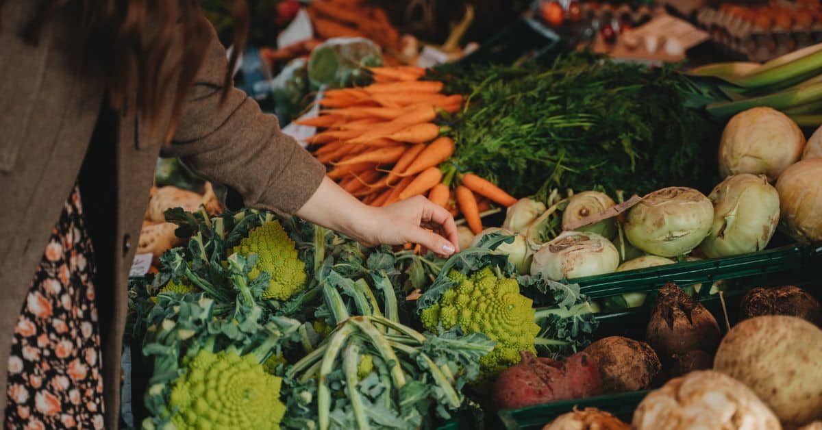 Woman shopping for vegetables at a farmer's market, seasonal foods