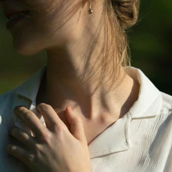 A woman places her hand near her neck and thyroid, Hashimoto's support