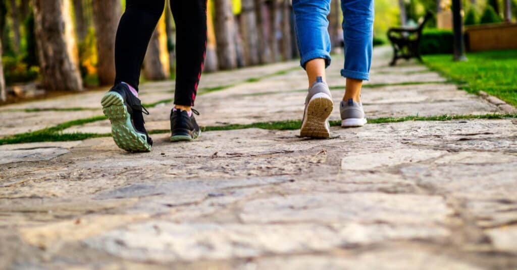Two sets of legs in walking shoes walking on the sidewalk outdoors, What is Blood Glucose Monitoring?