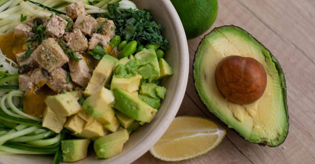 A keto dinner bowl with avocado, zuchinni noodles and tofu on a wooden table, Side Effects of Dieting