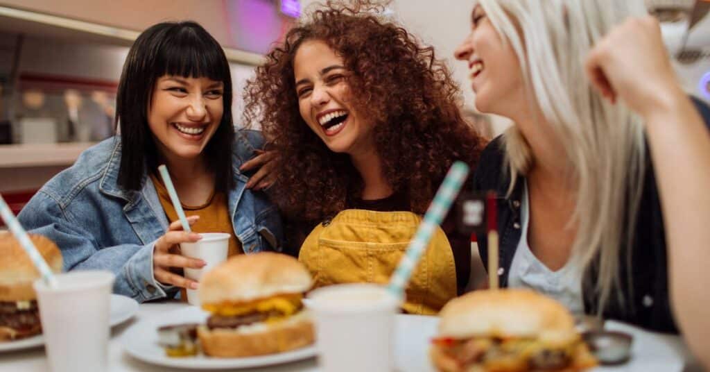 Dinner out with a group of three friends who are laughing, restrictive dieting