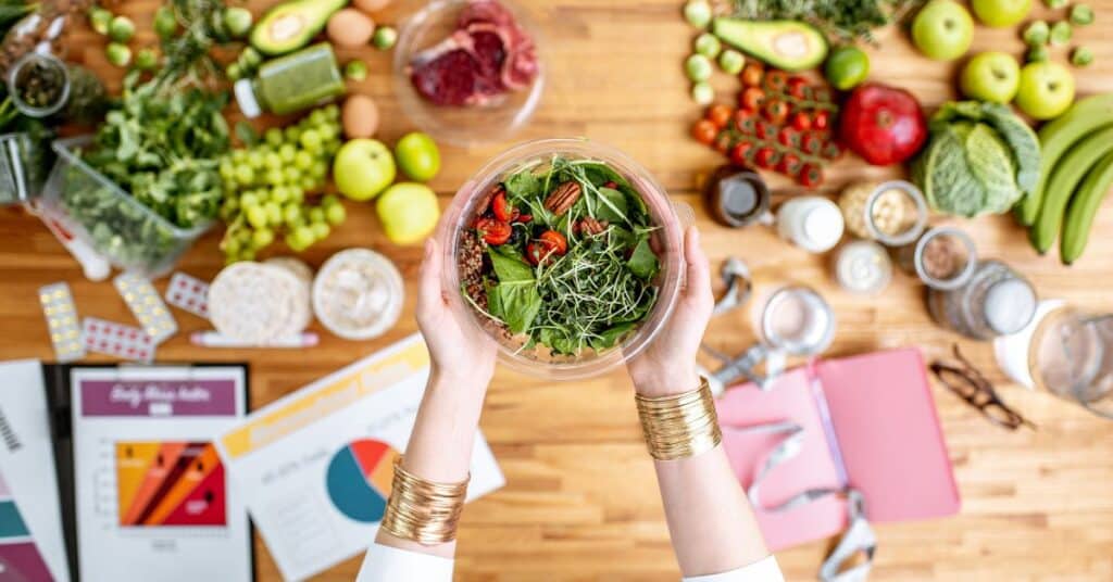 A dietitian holding a freshly made salad a table covered in fresh produce, what does a registered dietitian do